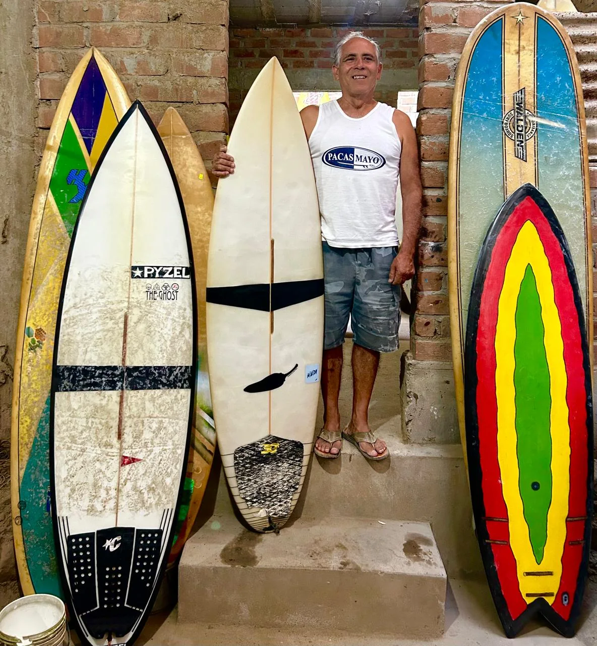 Gustavo Vargas in his workshop, among four surfboards leaning on the wall