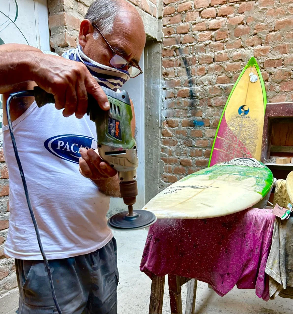 Gustavo Vargas working with the sander on a board, in his workshop