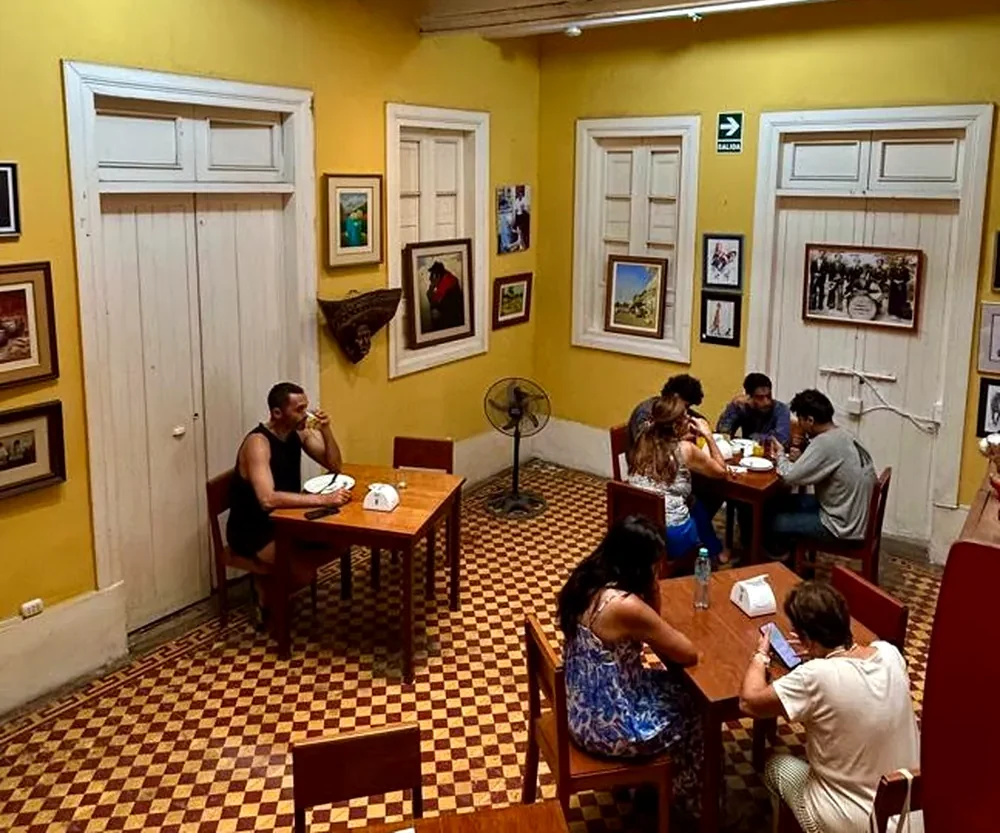 The café-bar room at lunchtime, with the tables taken and the wall of paintings
