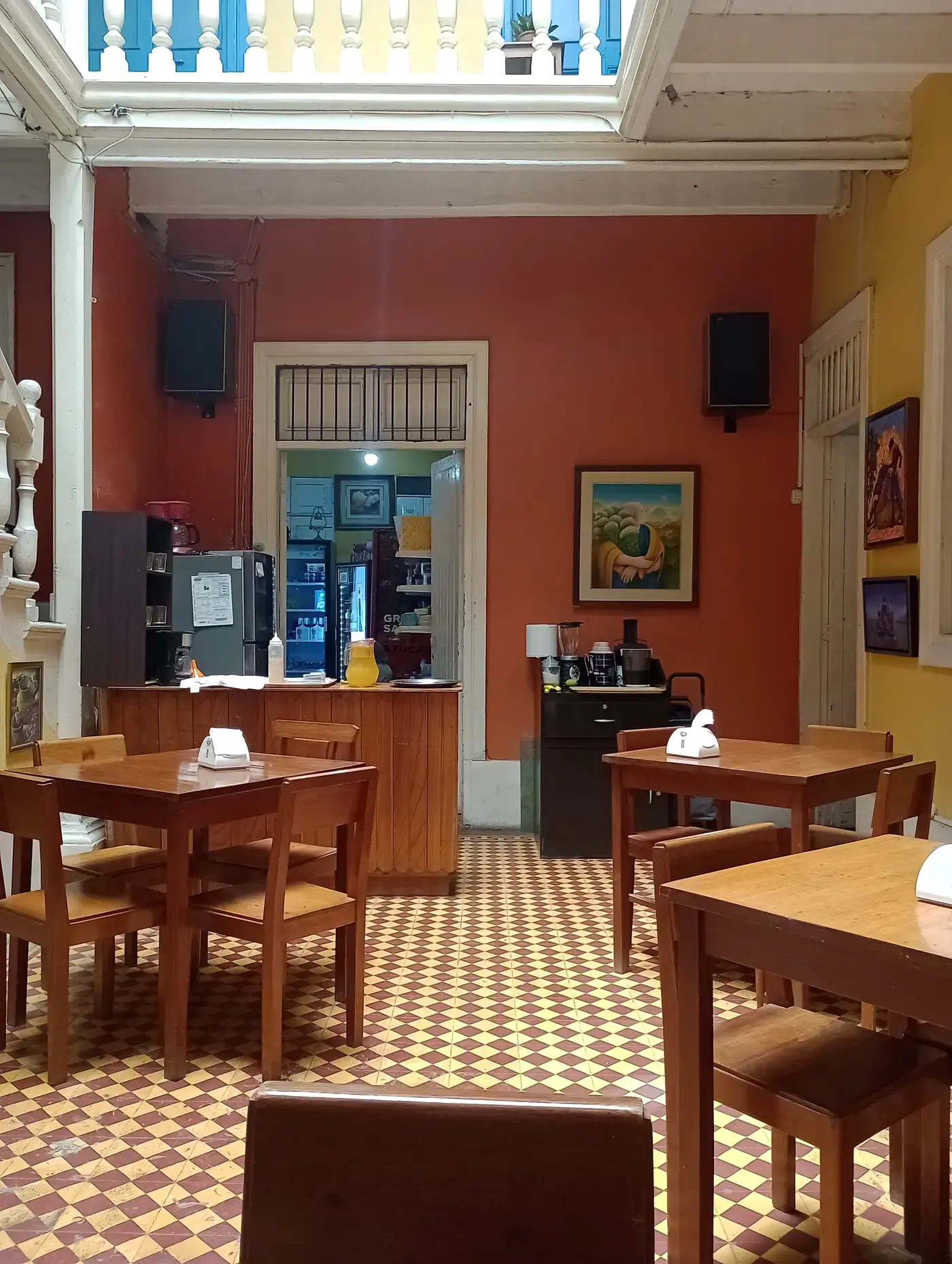 Comedor del Al Pacino Café-Bar, con mesas de madera y arte en las paredes