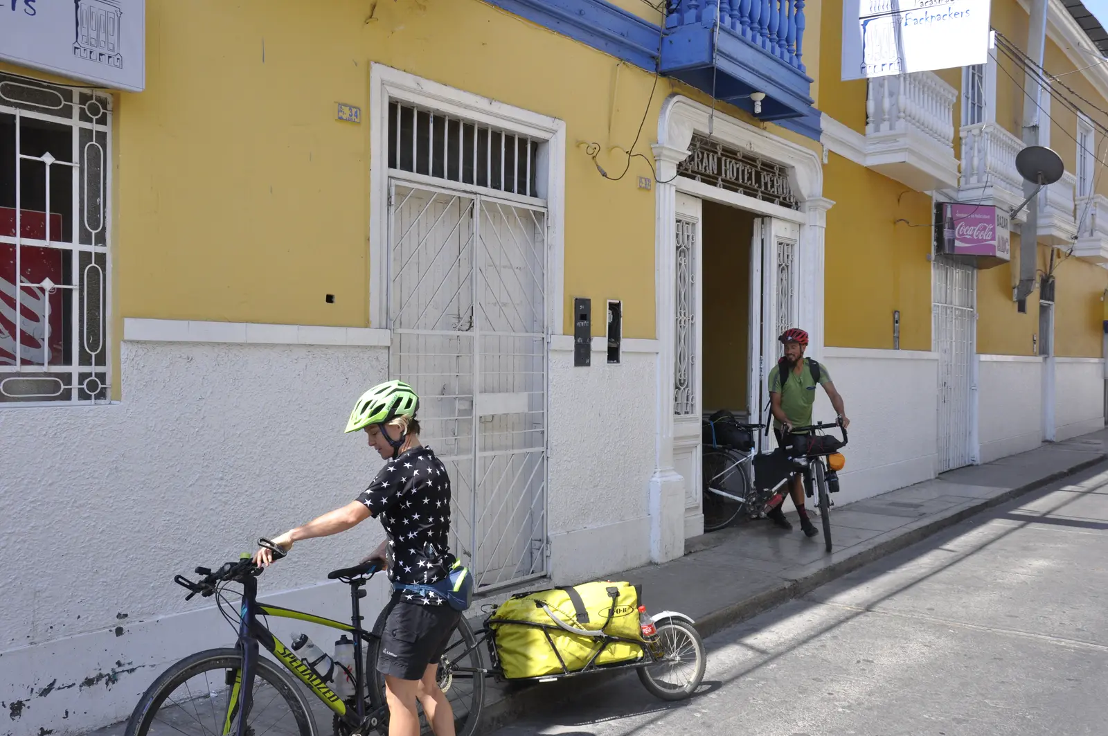 Dos cicloviajeros con sus bicicletas cargadas frente a la entrada del hostal, en Jr. Junín