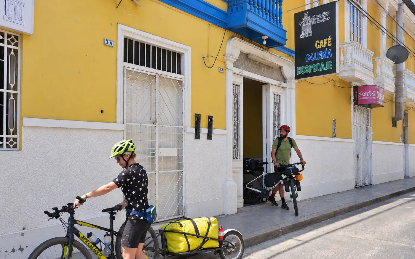 The yellow façade of the historic house, with the café, gallery and hostel sign, and two bicycle travellers on the pavement