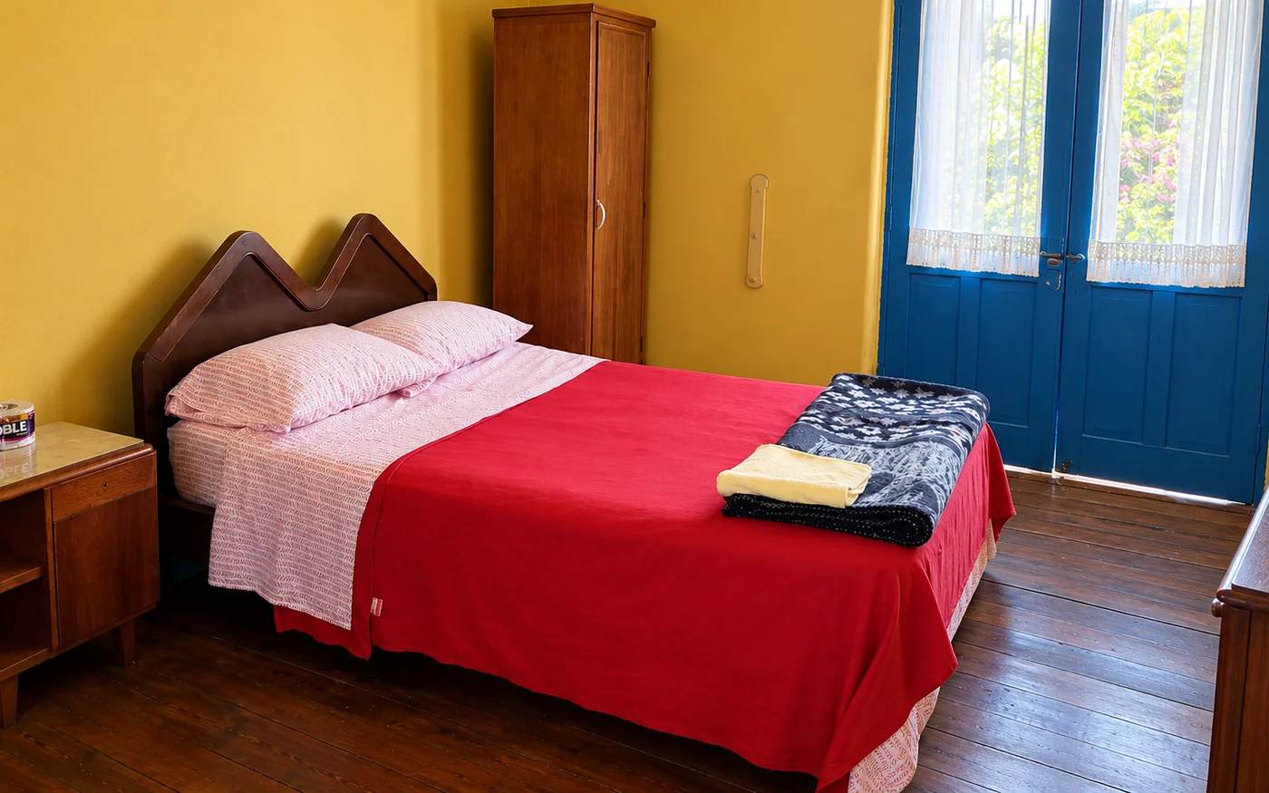 Room with a double bed in the historic house, with the yellow wall