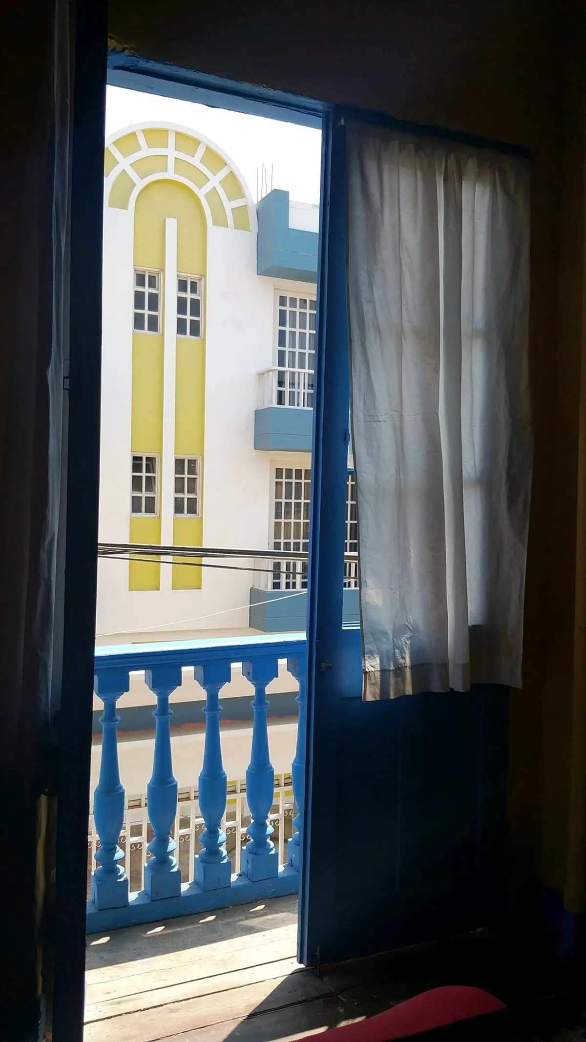 Balcón de una habitación tradicional, con puerta azul sobre la calle