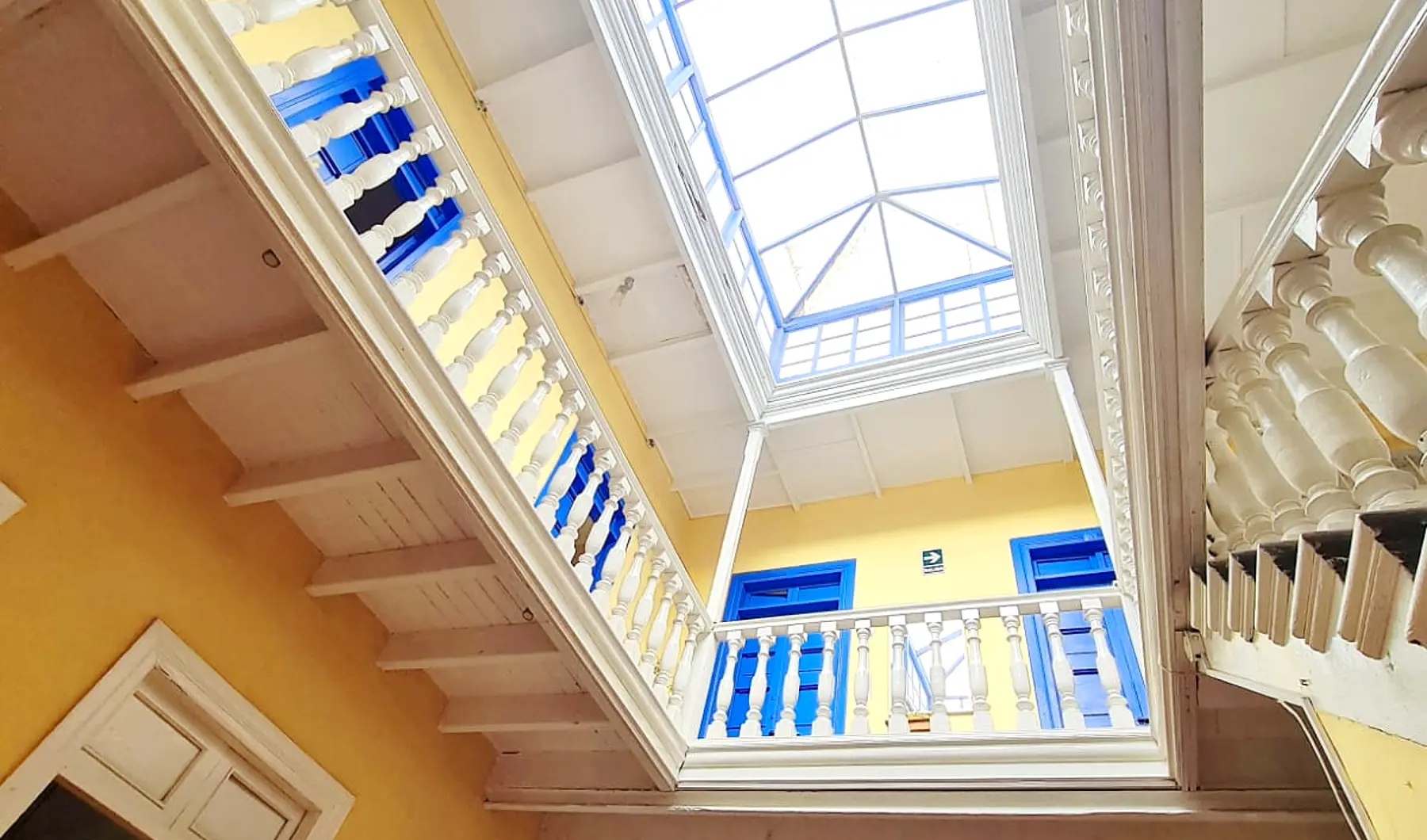 Patio interior de la casona, con el tragaluz y la balaustrada azul del segundo piso