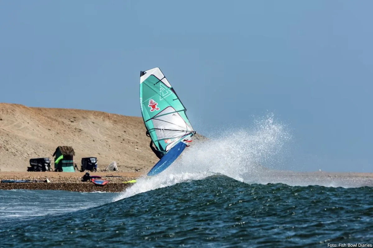 Windsurf sails crossing the bay at sunset
