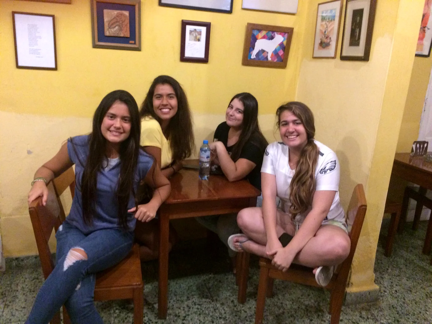 Four guests sitting at the caf&eacute; table, under the gallery paintings