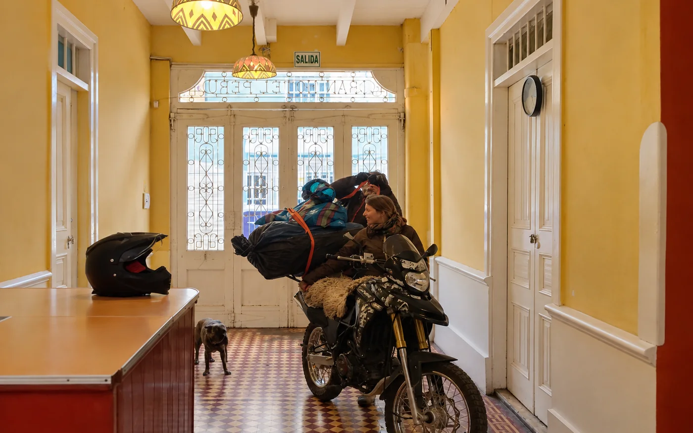 A loaded travel motorbike in the entrance hall of the old house, with the tiled floor and the stained glass at the back